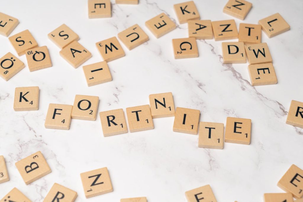 The Difference Between Board Games, Physical Games, and Digital Games Scrabble tiles spelling Fortnite on a marble surface, ideal for gaming concept art.