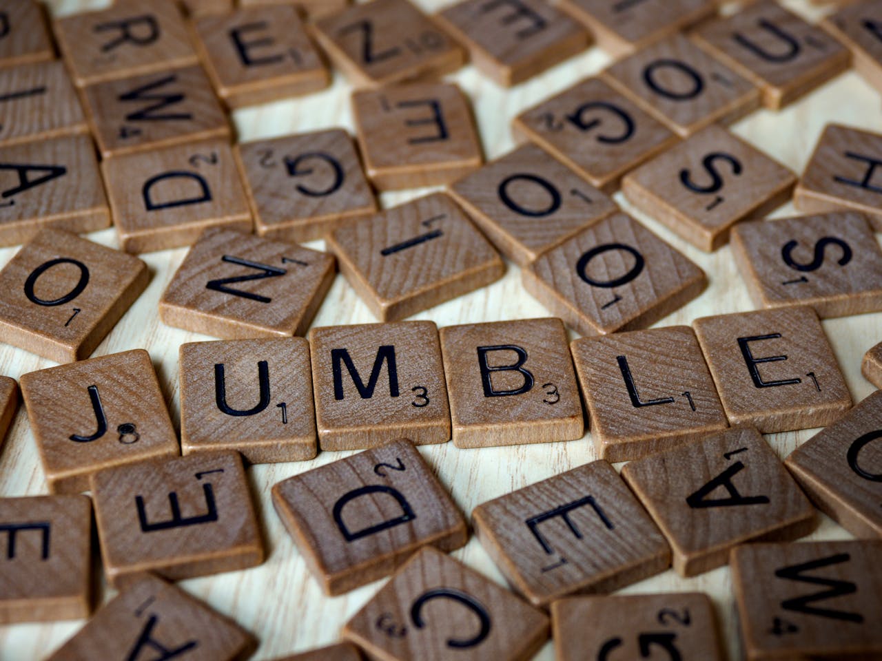 Offerings Close-up of scattered Scrabble tiles forming the word jumble on a wooden surface.